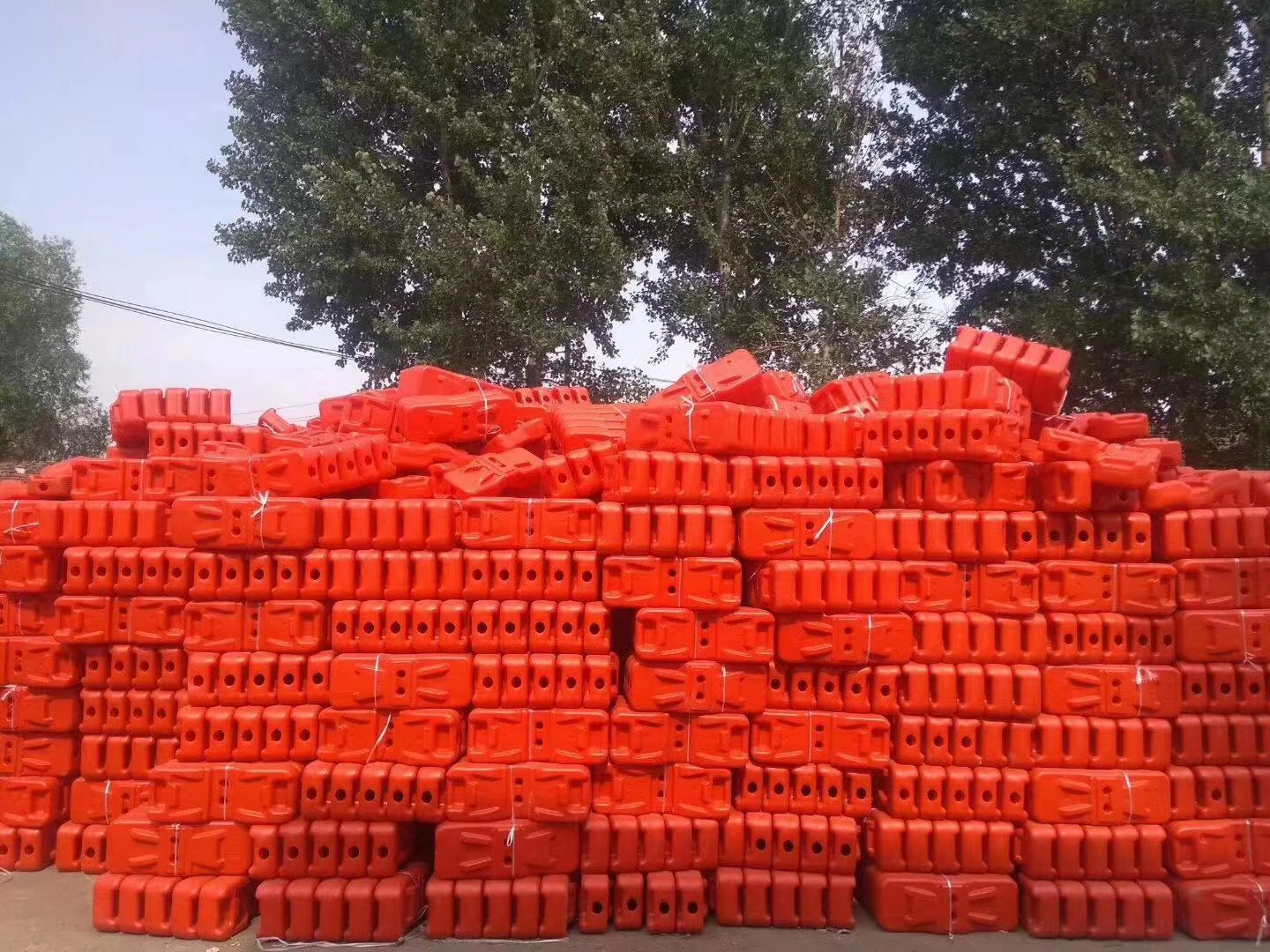 A large, organized stack of bright orange temporary fence feet and base systems, showcasing DB Fencing's robust production capacity. As Anping's sole manufacturer with its own plastic feet machine, we supply these essential, durable components for temporary fencing solutions globally, ready for immediate export.