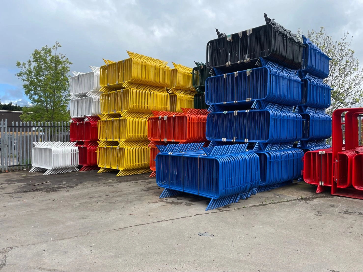 Vibrant stacks of hot-dipped galvanized crowd control barriers in various colors by DB Fencing, ready for dispatch. As a leading manufacturer in Anping, China, DB Fencing provides these durable barriers, essential for event management and public safety, to global distributors and event companies.
