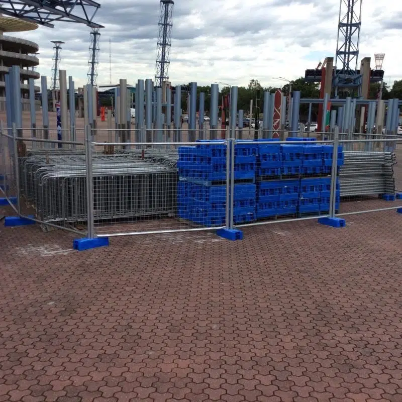 Stacked temporary fencing panels featuring DB Fencing's proprietary blue plastic Temporary Fence Feet & Base Systems, ready for deployment at a construction site or event in Australia. This visual highlights our factory-direct hot-dipped galvanized fencing with ISO9001/SGS certified plastic feet, manufactured to exceed AS 4687-2022/2007 compliance for harsh outdoor environments.