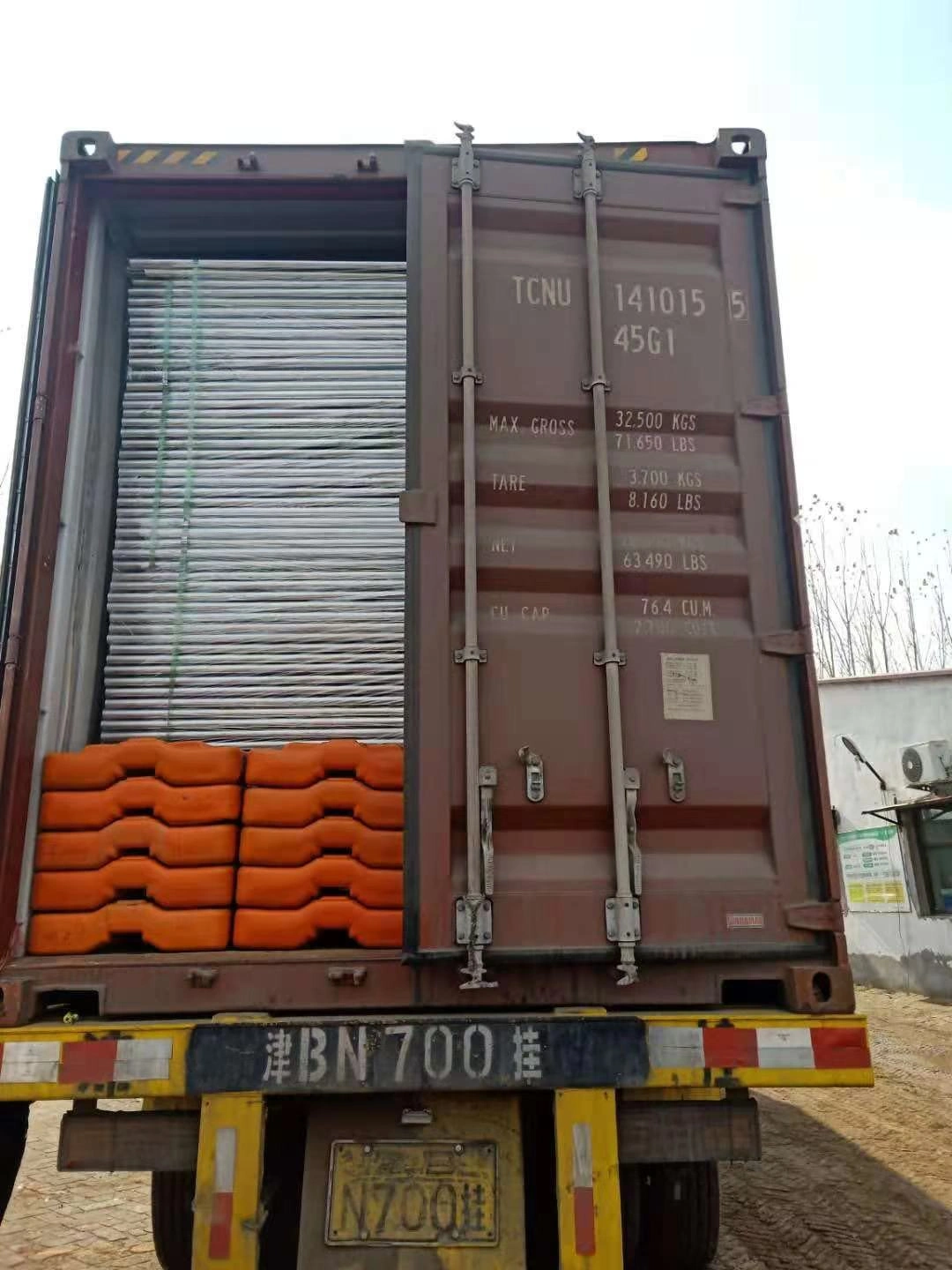 An open shipping container from DB Fencing, loaded with stacks of hot-dipped galvanized temporary fence panels and orange temporary fence feet & base systems, ready for bulk export. This image showcases DB Fencing's production capacity and efficient import logistics from Anping, China, supplying compliant fencing solutions for markets like Australia.