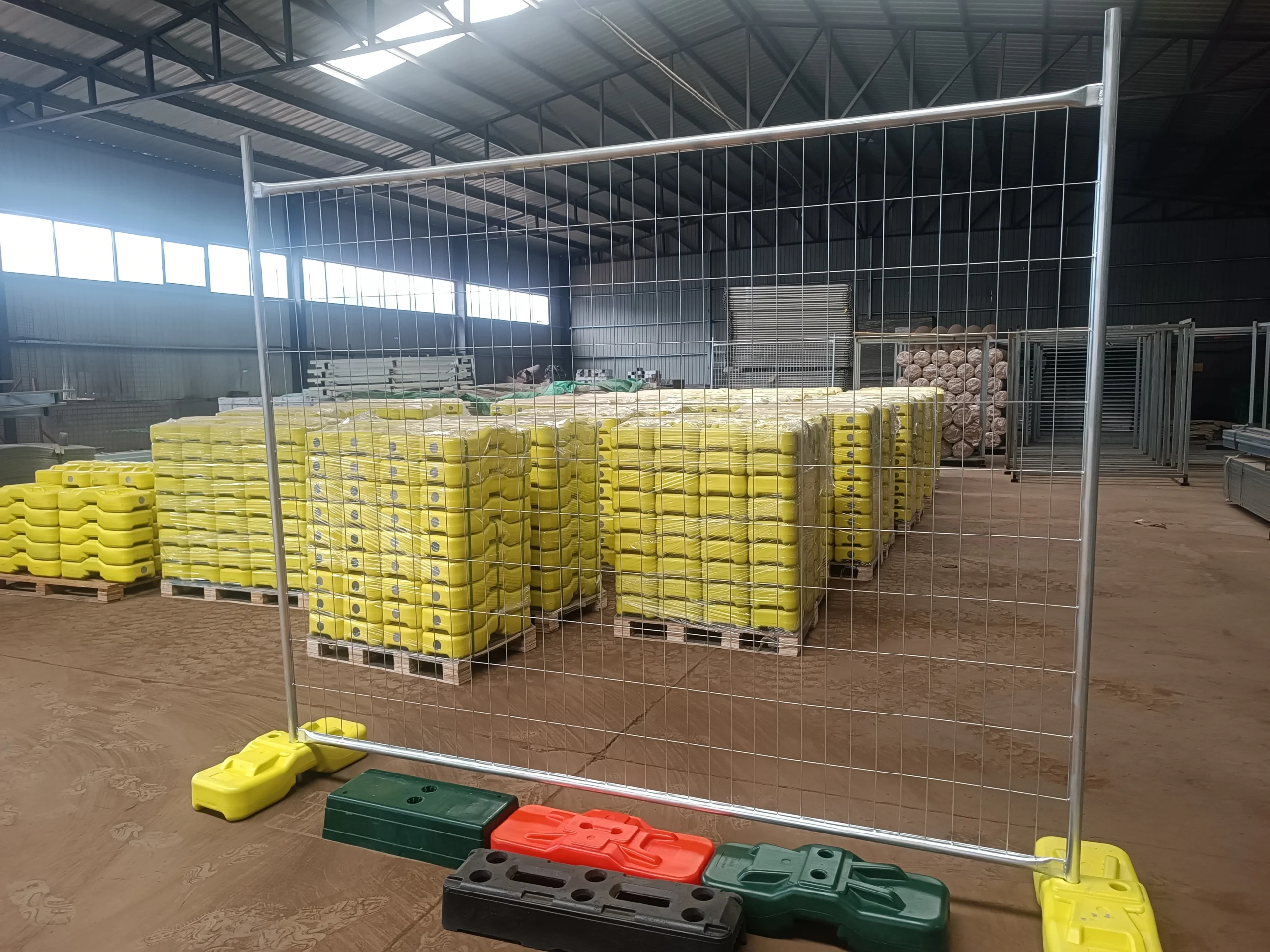 An interior view of the DB Fencing warehouse showcasing various temporary fence feet & base systems, including yellow, green, red, and black plastic bases, with large stacks of yellow bases on pallets in the background. This image highlights our in-house manufacturing capability as Anping's sole supplier with its own plastic feet machine for high-quality temporary fence feet and components, meeting Australian standards for durability.