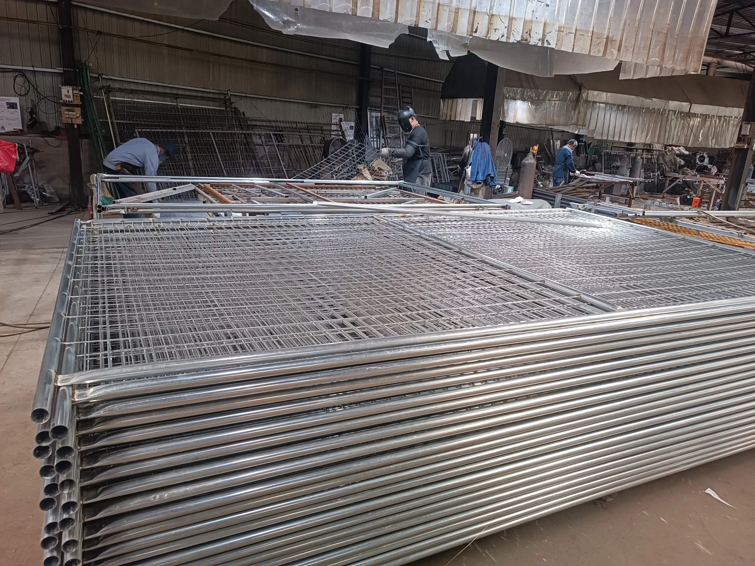 A large stack of hot-dipped galvanized temporary fencing systems for construction sites is prepared for shipment in the DB Fencing factory. This image highlights our robust production lines and quality manufacturing of compliant temporary fence panels for global B2B clients.