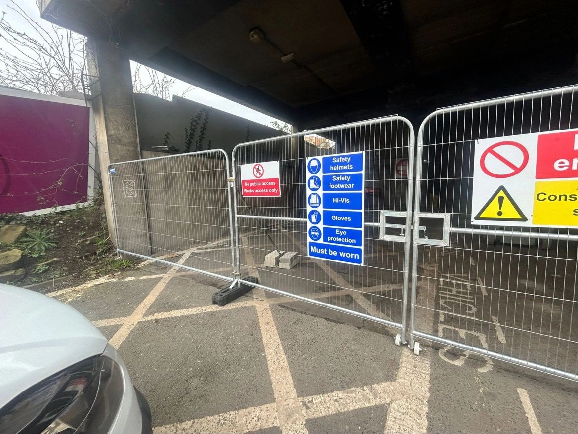 Galvanized temporary fencing systems, manufactured by DB Fencing, effectively barricade a construction site entrance with 'No public access, Works access only' and PPE requirement signs. These robust temporary fencing systems for construction sites provide essential security and site management for B2B clients, ensuring compliance and safety.