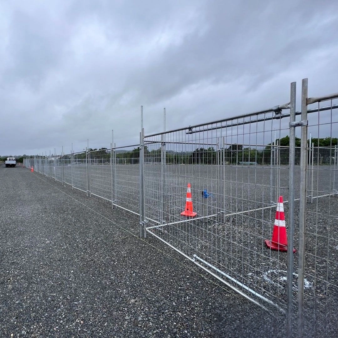 An extensive setup of DB Fencing's durable temporary fencing systems for construction sites, featuring hot-dipped galvanized mesh panels and sturdy bases on a gravel surface under a cloudy sky, ensuring secure perimeter control. These high-quality temporary fence solutions are designed for quick installation and compliance with Australian standards, ideal for B2B clients in construction and civil engineering.