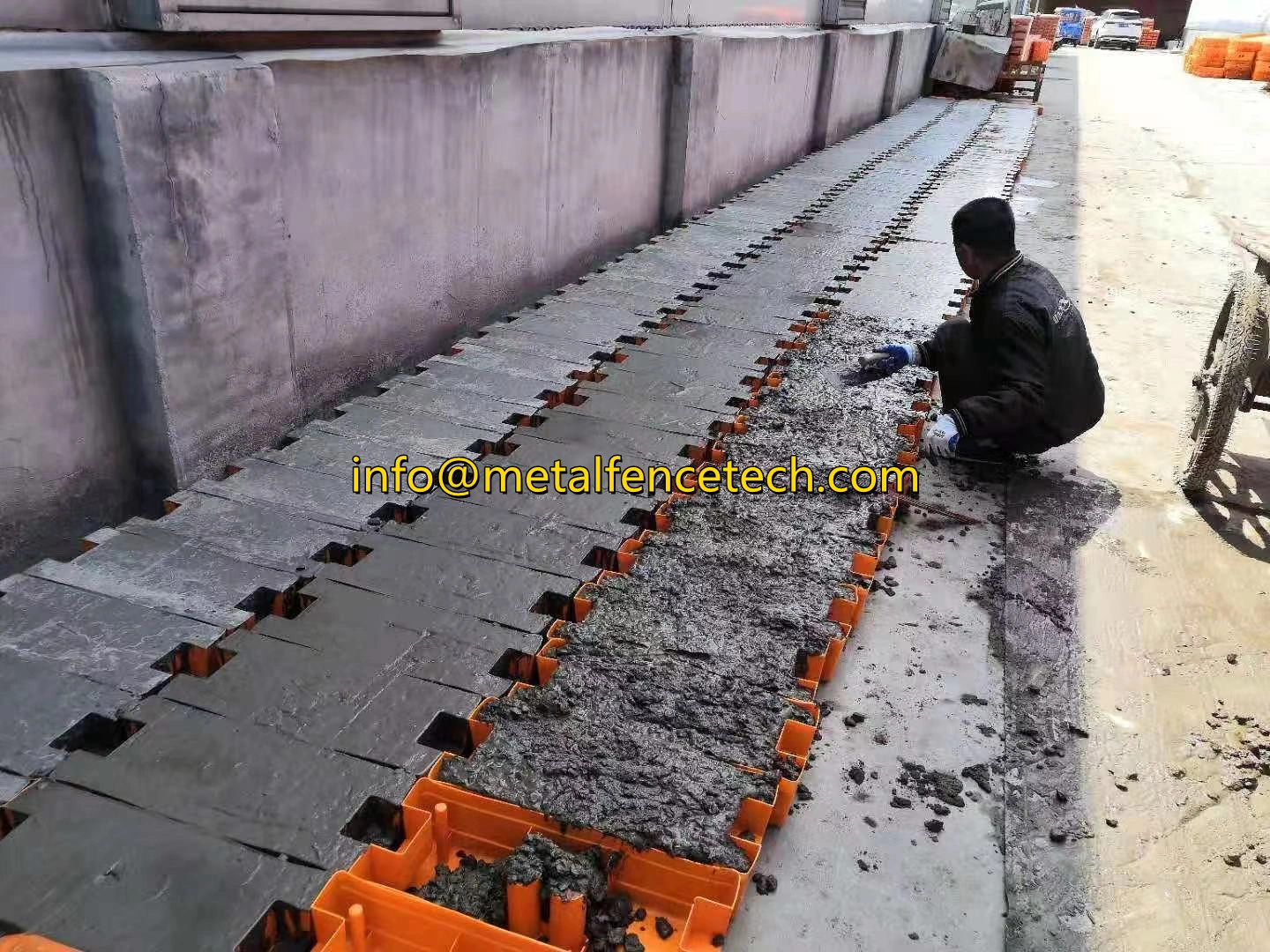 A DB Fencing worker meticulously fills our high-quality orange plastic temporary fence feet with concrete, showcasing our advanced production of durable Temporary Fence Feet & Base Systems. This manufacturing process ensures superior stability and compliance for temporary fencing applications, reinforcing DB Fencing's position as a leading supplier.