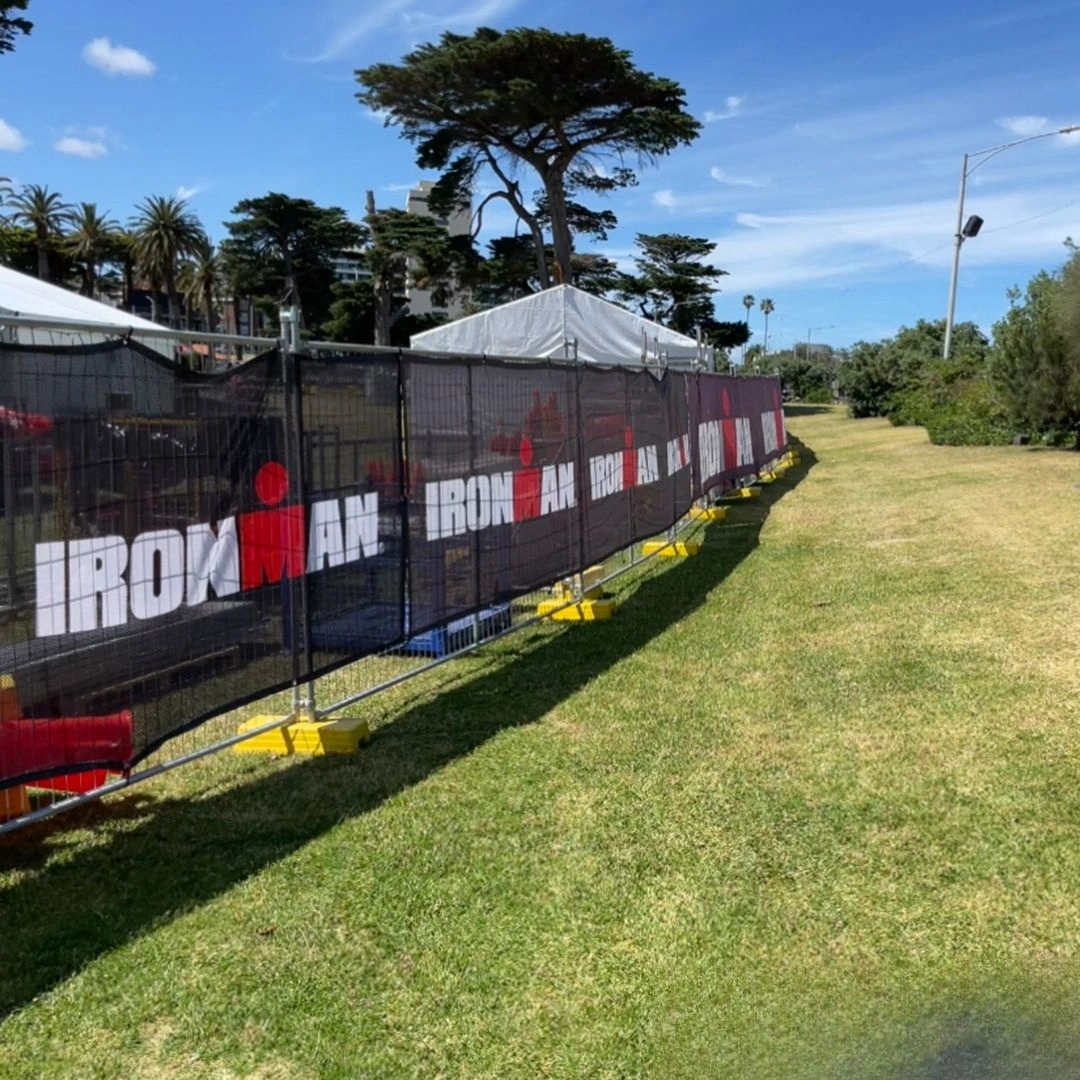 This image features DB Fencing's custom-branded crowd control barriers prominently displaying the IRONMAN logo, supported by our signature yellow temporary fence feet for an outdoor event. As a leading manufacturer, Anping Deban Metal Wire Mesh Products Co., Ltd provides compliant and durable temporary fencing systems, ideal for event management companies seeking robust perimeter solutions.
