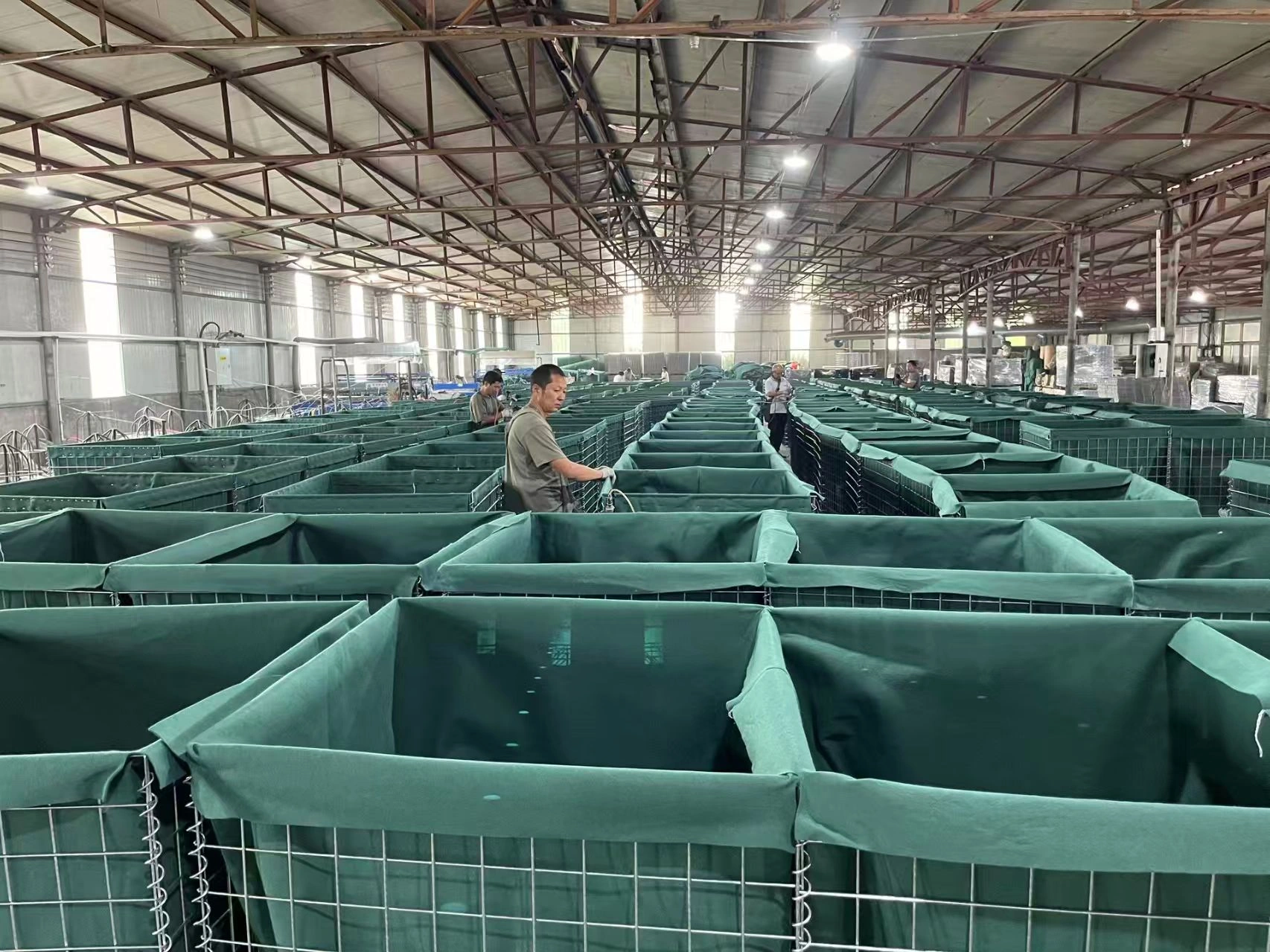 Rows of DB Fencing Hesco Barriers lining the factory floor, demonstrating mass manufacturing capacity for construction site security.