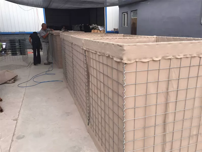 Factory view showing Anping Deban Metal Wire Mesh Products Co., Ltd workers fabricating Hesco Barriers using heavy-duty galvanized welded wire mesh cages for civil engineering applications.