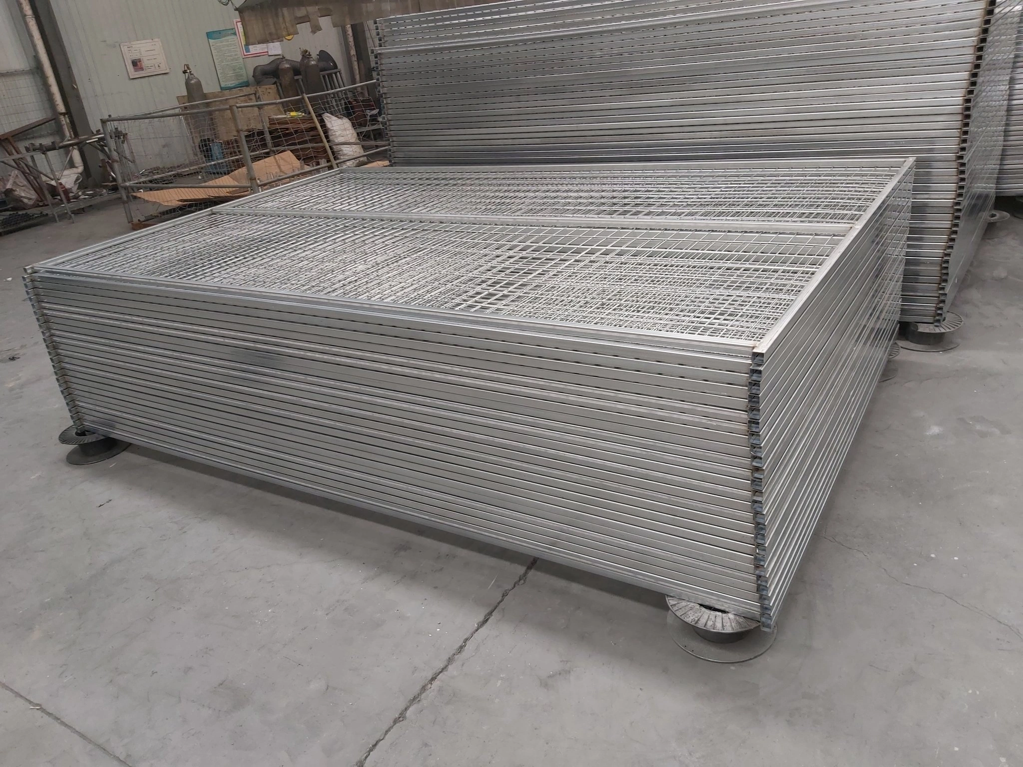 Large stacks of hot-dipped galvanized temporary fencing systems ready for bulk export, manufactured by DB Fencing (Anping Deban Metal Wire Mesh Products Co., Ltd) for secure construction site perimeters and crowd control applications.