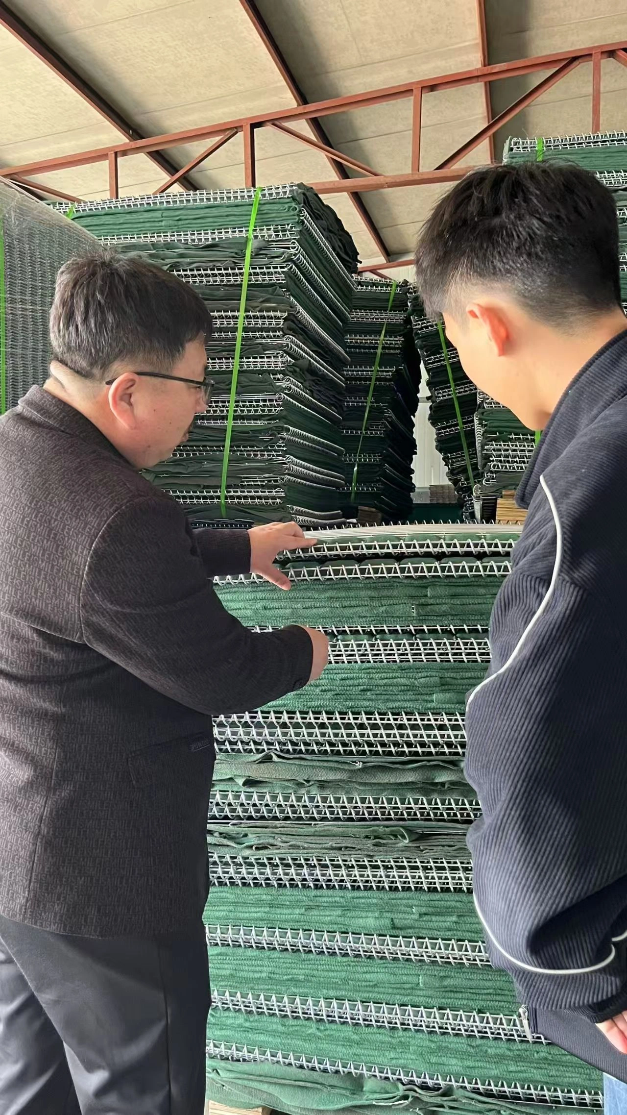Anping Deban Metal Wire Mesh Products (DB Fencing) factory staff conducting quality inspection on stacks of Hesco barrier wire mesh panels. Our production lines ensure compliance with Australian standards for durable site security solutions.