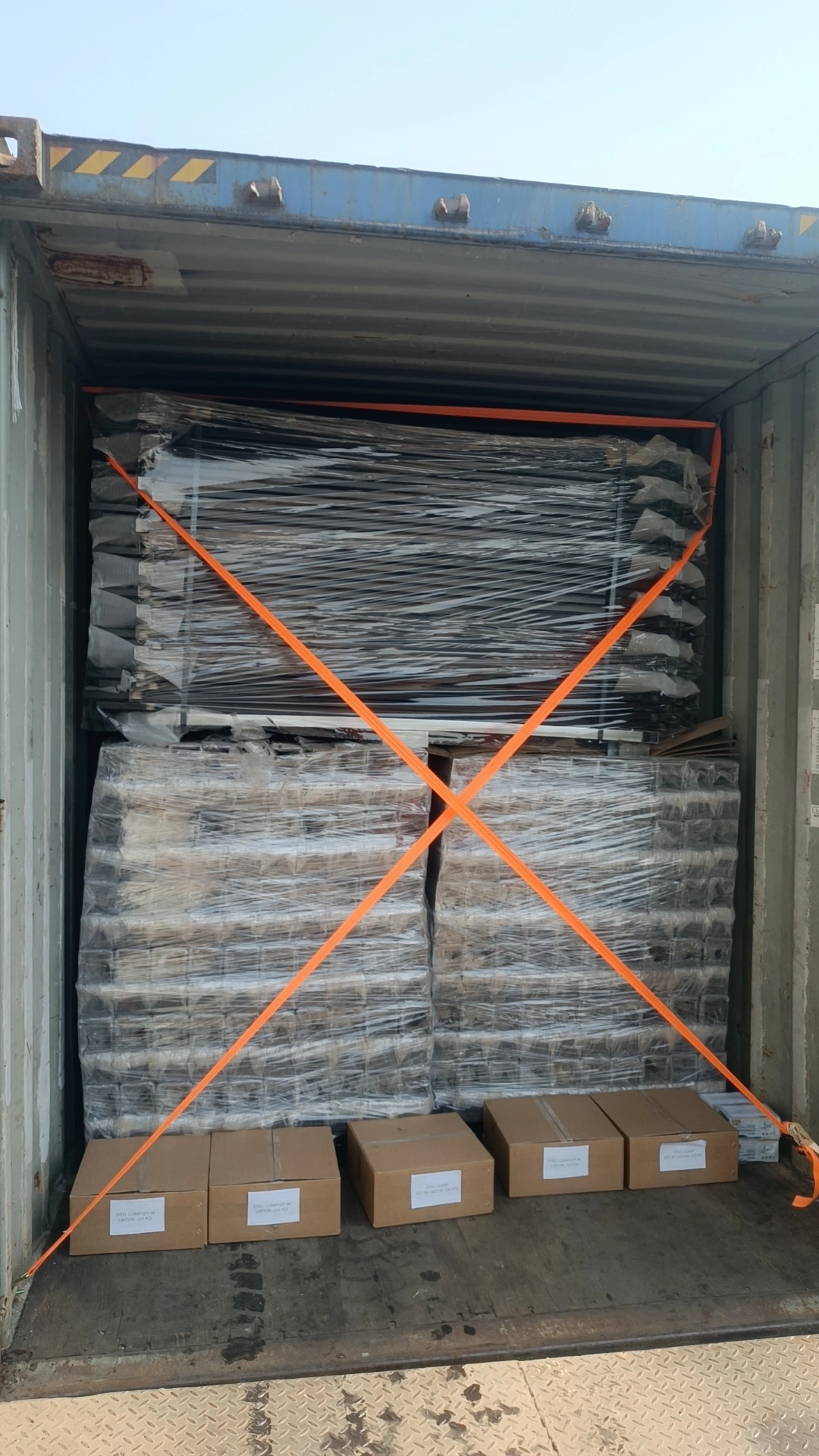 Large container loaded with plastic-wrapped Hesco Barriers and temporary fencing secured with orange straps, prepared for shipping from DB Fencing.