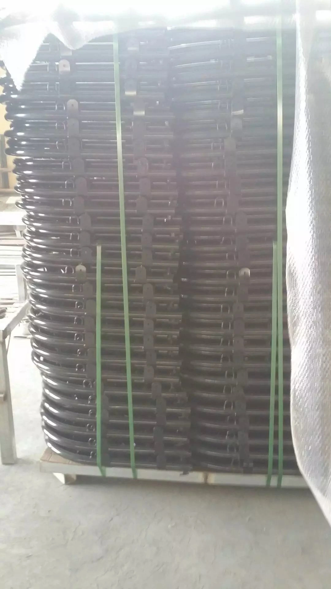 A large stack of hot-dipped galvanized steel components, featuring the distinctive curved design of Crowd Control Barriers frames, awaiting bulk export from DB Fencing's manufacturing facility. These robust frames demonstrate our production strength and readiness for B2B distribution to clients globally, upholding our commitment to quality and compliance.