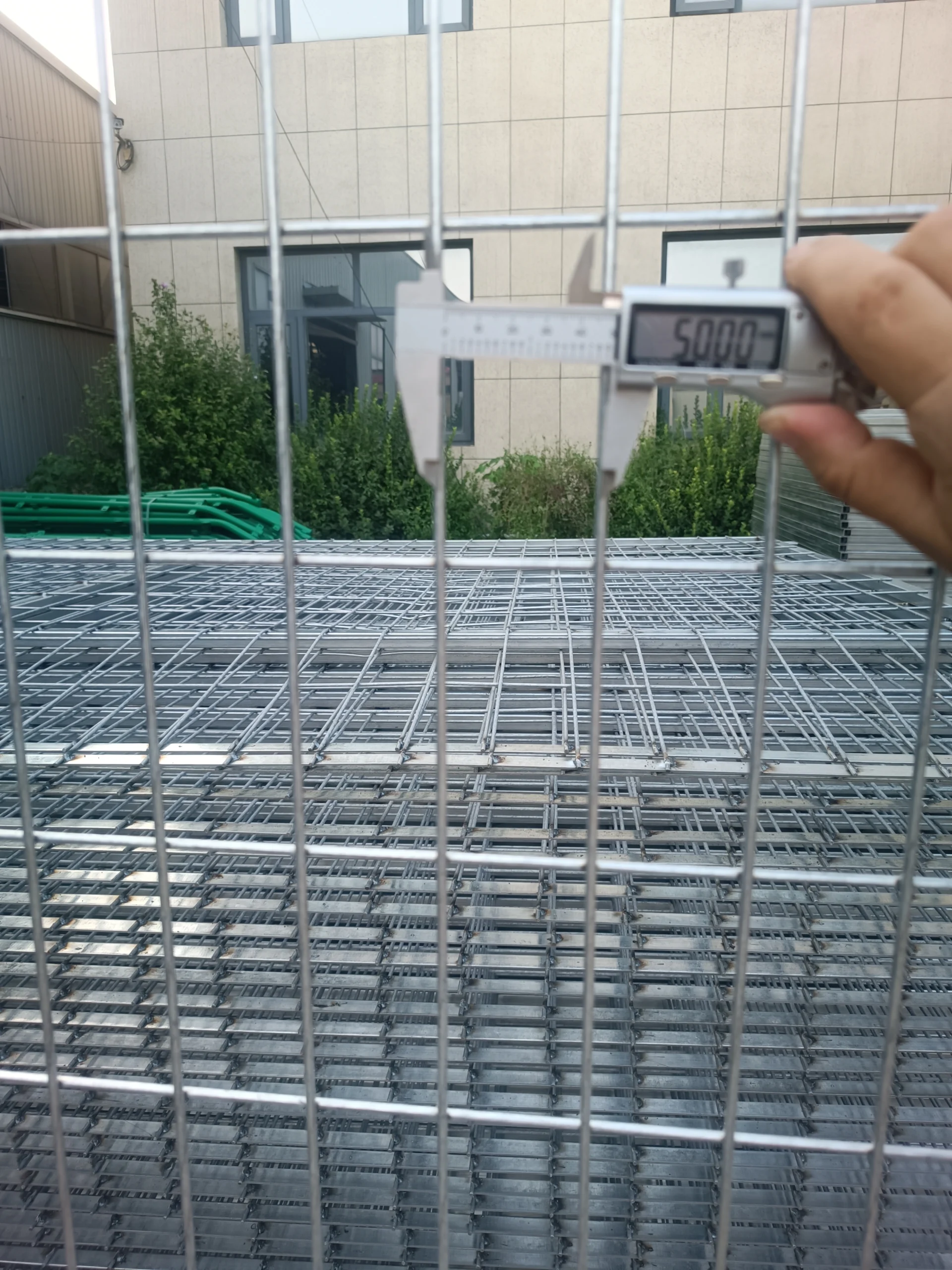 A close-up of heavy-duty wire mesh panels from DB Fencing being measured on a production floor, showcasing the precision of our temporary fencing systems for construction sites. Our 2,000 sets/week capacity ensures global delivery of compliant, galvanized security fencing.