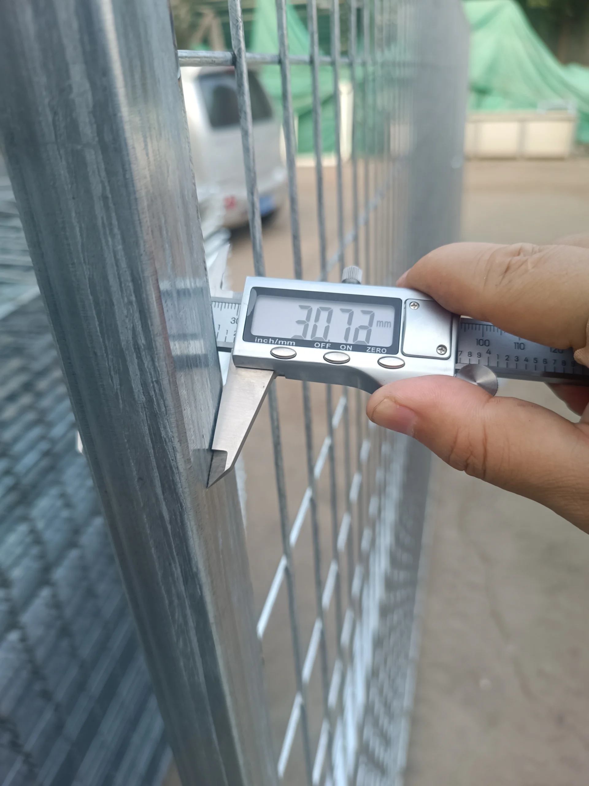 Anping Deban Metal Wire Mesh Products Co., Ltd demonstrates quality control with digital calipers measuring wire thickness on our temporary fencing systems for construction sites. This close-up verifies compliance with AS 4687 and ensures high durability for B2B contractors and distributors.